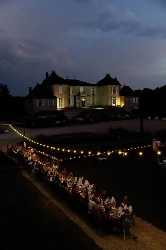 Dîner de mariage sous les guirlandes lumineuses devant un château