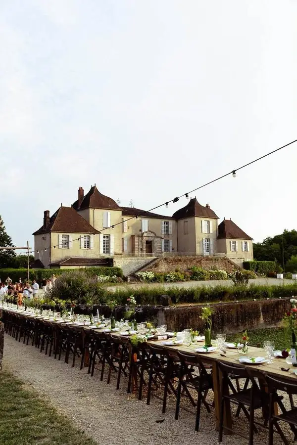Longue table de réception dressée devant un château au crépuscule