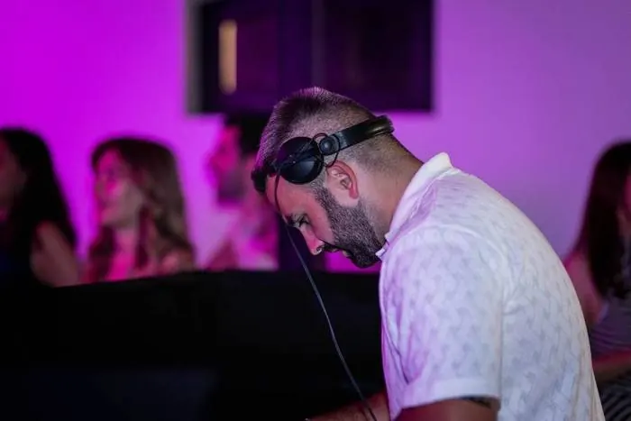 Loïc aux platines dans une ambiance violette, invités derrière