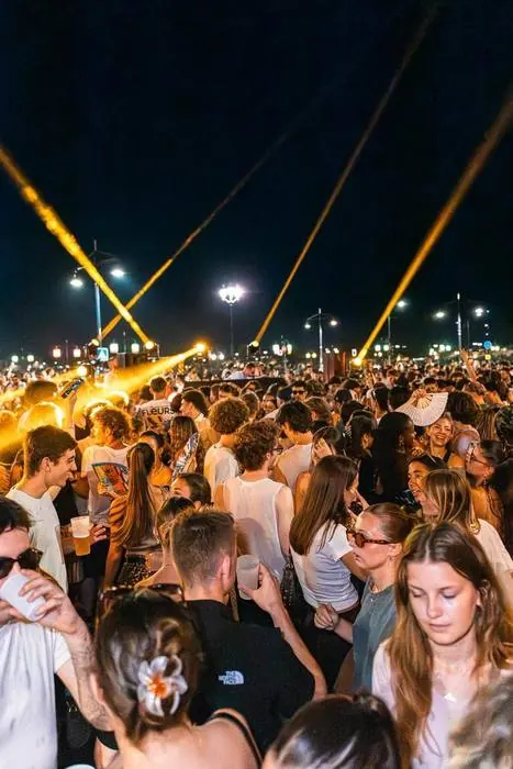 Foule en fête sous les faisceaux lasers lors d'une soirée en plein air